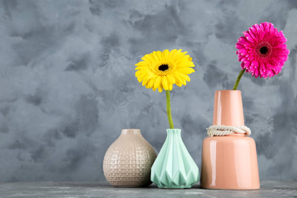 istock Different ceramic vases with gerbera flowers on gray background 1191409929