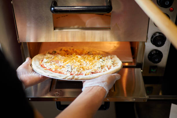 istock baker puts pizza in the oven 1191411313