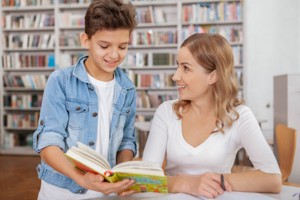 istock Cute young boy studying with his mom at the library 1191413337