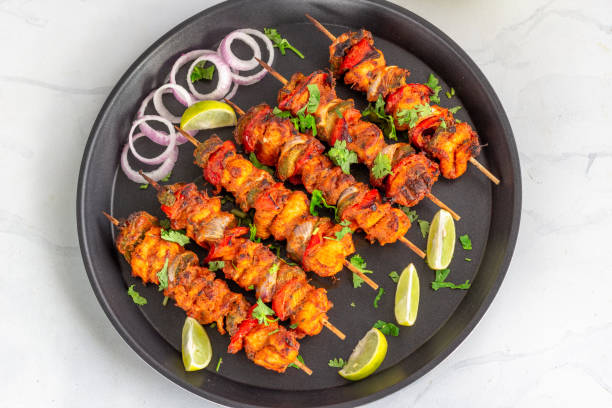 Chicken Tikka on the Skewers Directly Above Photo Chicken Tikka Skewers on a Black Plate with Lemon and Onion Rings, Directly Above Photo, Chicken Appetizer Photography chicken skewer stock pictures, royalty-free photos & images
