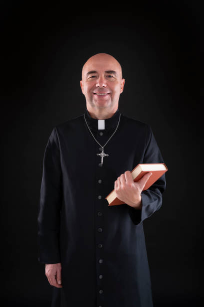 istock Priest holding bible hairless in low key black 1191417287