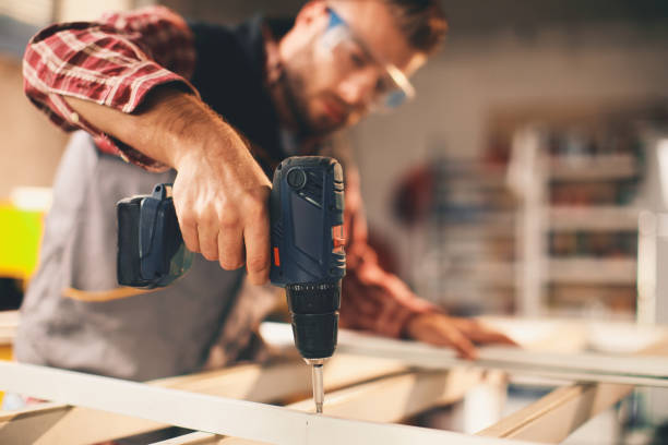 jeune homme travaillant avec la perceuse dans l'atelier - menuisier photos et images de collection