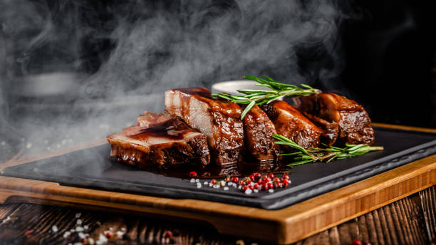 concepto de comida americana. costillas de cerdo a la brasa con salsa a la parrilla, con humo, especias y romero. imagen de fondo. copiar espacio - rib fotografías e imágenes de stock