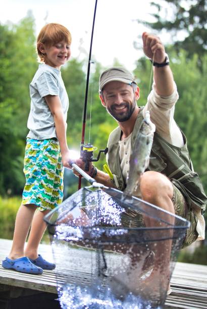 istock Smiling father and son catching fish on pier 1191427750