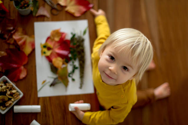 istock Sweet child, toddler boy, applying leaves using glue 1191429481
