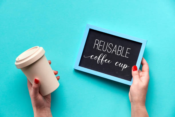 Bamboo coffee cup, keep cup or travel mug in female hand on blue mint background. Creative flat lay, top view image, text taza de café de bambú, mantener la taza o taza de viaje en la mano femenina sobre fondo de menta azul. creativo plana, vista superior, texto