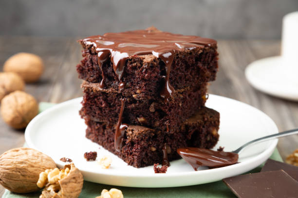 brownies délicieux avec le chocolat fondu sur une pile - nappage photos et images de collection