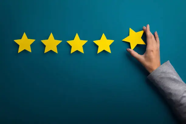 Photo of Woman hand giving five star rating on green