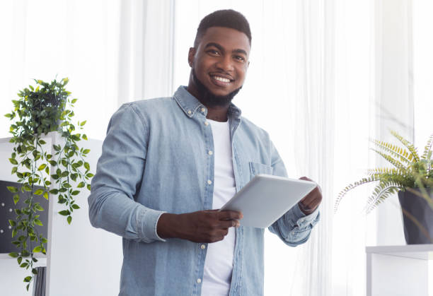 istock Young black businessman with digital tablet near window in office. 1191432879