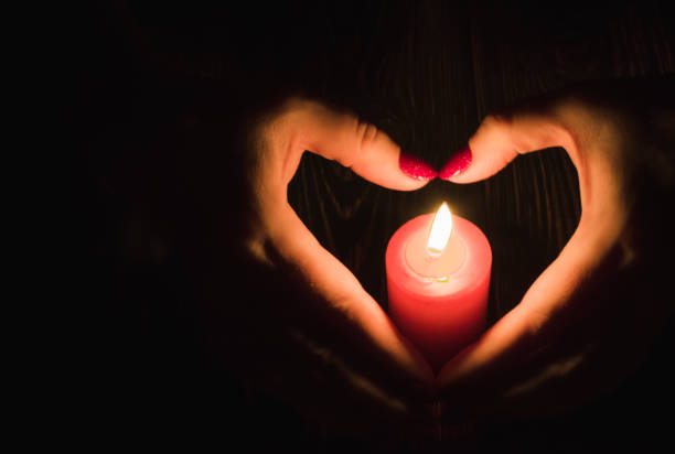 istock Heart-shaped female hands around  burning red candle 1191436442