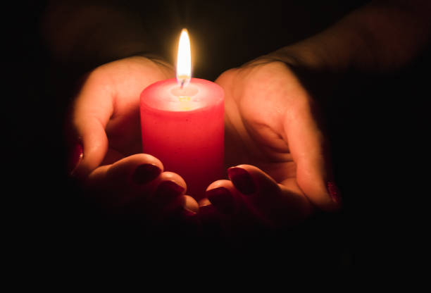 istock Female hands holding a burning candle in the dark 1191436447