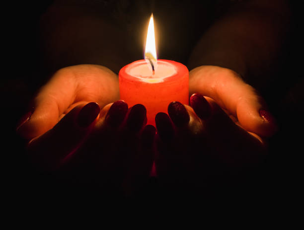 istock Female hands holding a burning candle in the dark 1191436485