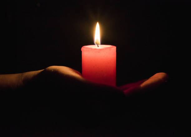 istock Female hands holding a burning candle in the dark 1191436491