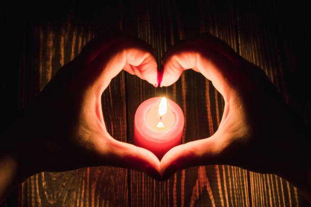 istock Heart-shaped female hands around  burning red candle 1191436503