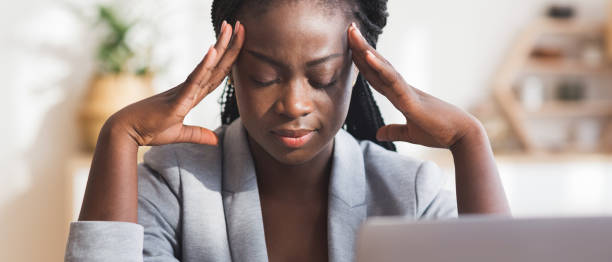 Tired black businesswoman suffering from migraine at workplace in office Hard work. Tired african american businesswoman suffering from migraine at workplace in office, panorama acute angle stock pictures, royalty-free photos & images