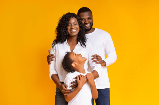 familia negra amorosa con hija abrazando y sonriendo a la cámara - photography looking three people mother fotografías e imágenes de stock