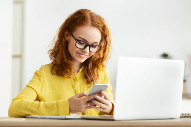 istock Freelance woman using smartphone near laptop computer in office 1191437493