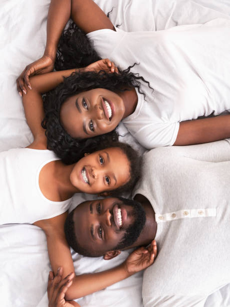 вид на радостную афро семьи отдыха в постели вместе - couple affectionate relaxation high angle view стоковые фото и изображения
