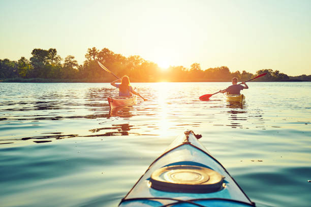 gente kayak durante la puesta del sol en el fondo. diviértete en tu tiempo libre. - lake fotografías e imágenes de stock