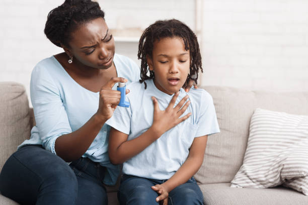 black mother holding asthma inhaler for daughter - asthmatic imagens e fotografias de stock