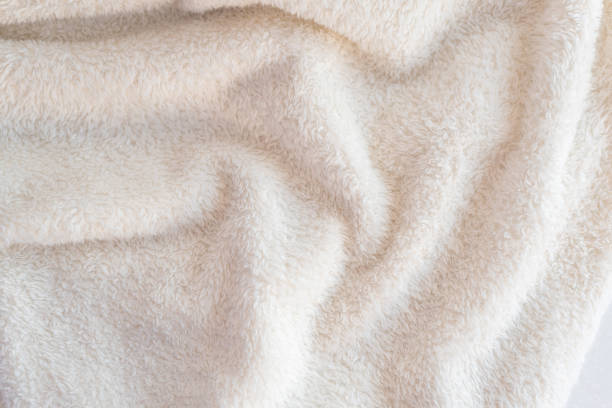 Un plaid confortable doux fait de tissu blanc avec la pile se trouve dans de beaux plis