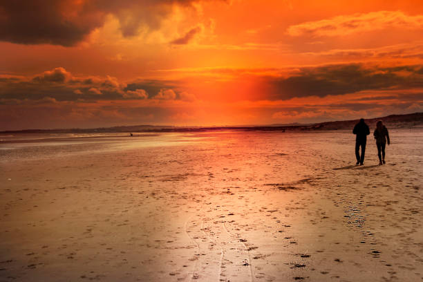 istock Beautiful sunset and a couple walking on a beach. 1191451700