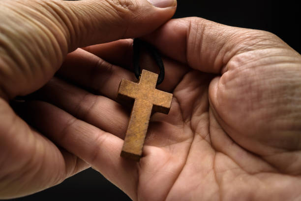 el crucifijo está en manos de un hombre que está orando por la bendición de su dios con fe. - praying human hand worshipper wood fotografías e imágenes de stock