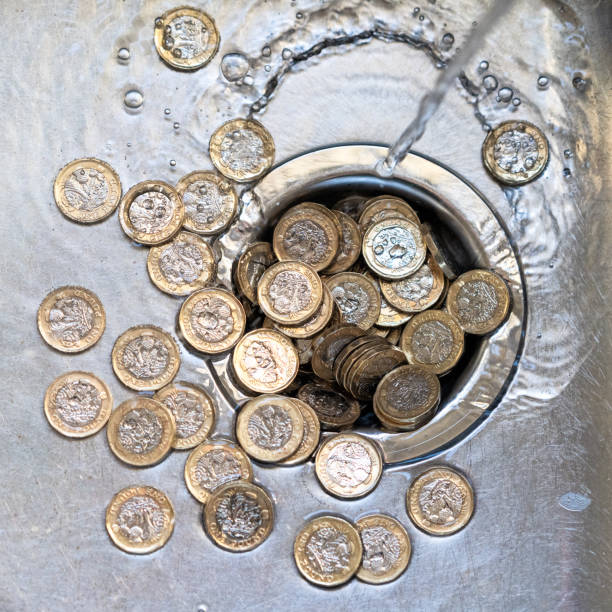dinero que va por el drenaje - british coin coin falling british currency fotografías e imágenes de stock