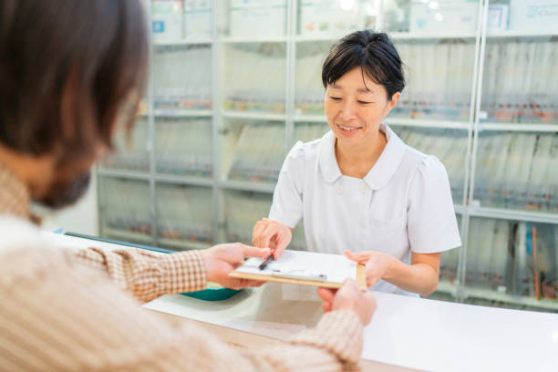 病院のレセプションで患者から医療記録を受け取る女性医師 - dentist office clinic dentist office ストックフォトと画像