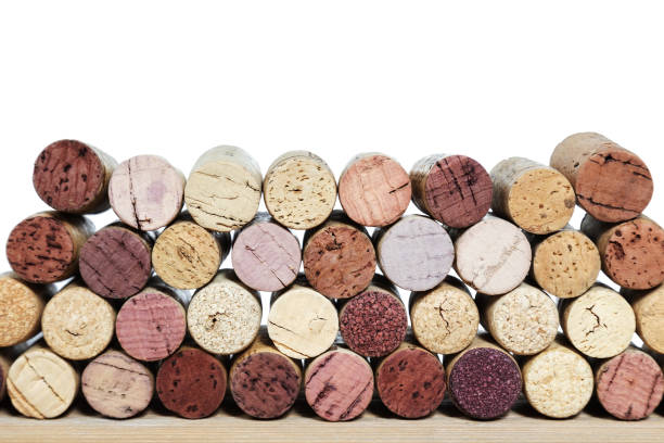 tappi luminosi multicolori da bottiglie di vino su un tavolo di legno isolato su uno sfondo bianco. file di tappi di sughero con macchia di vino rosso. - cork tops foto e immagini stock