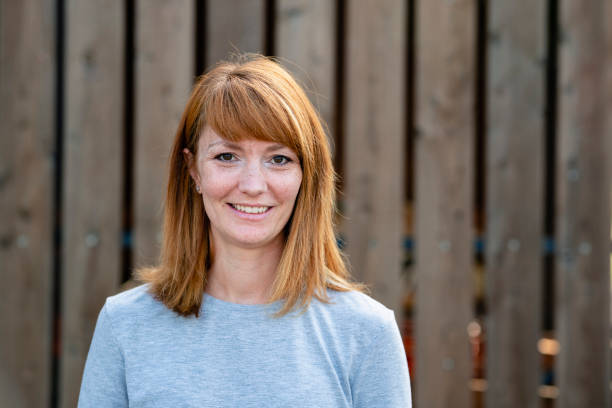 A Mid Adult Redhead Woman A portrait of a mid adult woman smiling while looking at the camera. mid length hair stock pictures, royalty-free photos & images