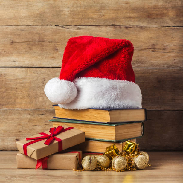 istock A stack of books, Santa Claus's cap, Christmas-tree decorations, gift boxes on a wooden background. Concept of New Year and Merry Christmas. 1191463368