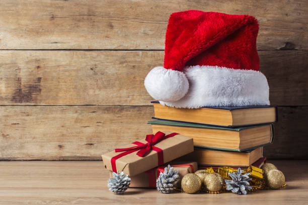 istock A stack of books, Santa Claus's cap, an alarm clock, cones, Christmas-tree decorations, gift boxes on a wooden background. Concept of New Year and Merry Christmas. 1191463482