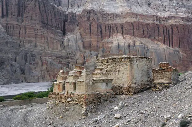 Photo of Buddhist chortens and ruins among the shale mountains in the vicinity of Chusang. Trekking to the Upper Mustang, Nepal.