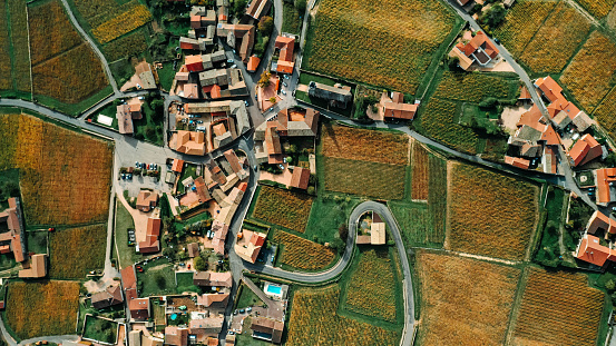 Toma aérea de un pueblo francés con techos naranjas, caminos sinuosos y rodeado de viñedos - foto de stock photo