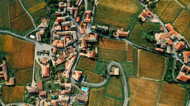 Photo of Aerial shot of a French village with orange roofs, winding roads and surrounded by vineyards - stock photo