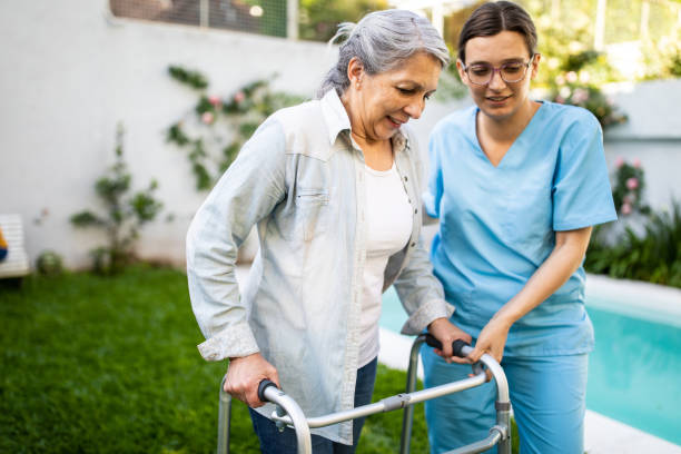 You're doing so well Young female nurse supporting old woman to walk outdoors with mobility walker, in retirement home walking aide stock pictures, royalty-free photos & images