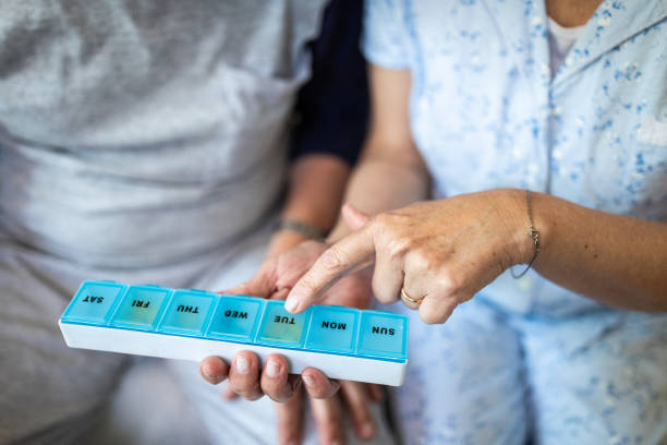 couple taking daily supplements from plastic pill organizer box - vitamin pill capsule equipment data imagens e fotografias de stock