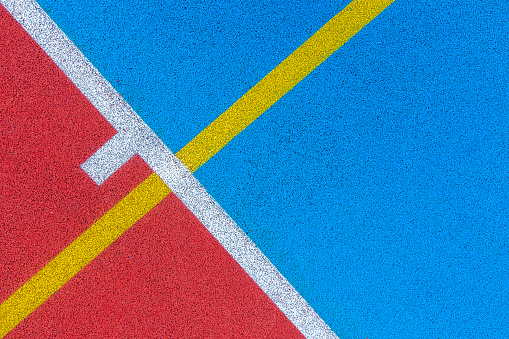 Colorful sports court background. Top view to red and blue field rubber ground with white and yellow lines outdoors.