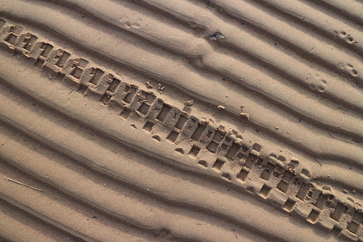 motorcycle wheel imprint on the sand of a beach