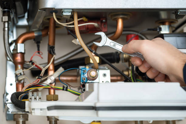 techniker hält schraubenschlüssel vor kombi-gaskessel - water heater installing boiler radiator stock-fotos und bilder
