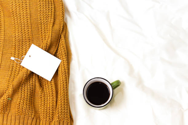 istock coffee cup and empty tag above woolen scarf on bed, hello winter concept 1191486263