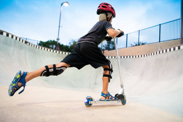 A 7 Year Old Boy On A Scooter At The Skate Park stock photo