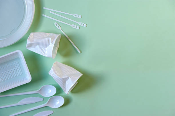istock Plastic cups, spoons, knives, stirrers, plate and box on green 1191495866