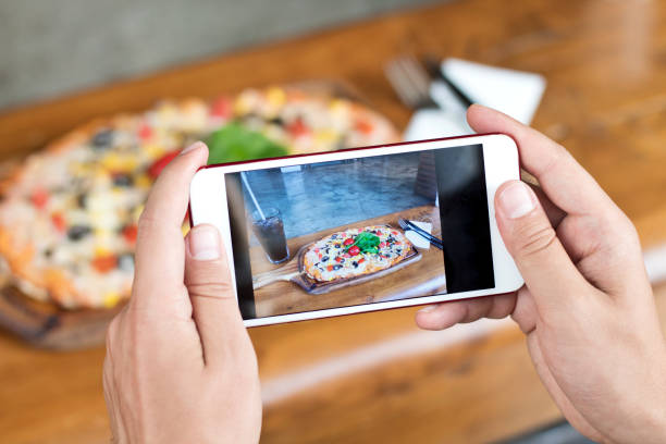 male hand making a photo of pizza, with a mobile phone, close up, horizontal - fotografia imagem imagens e fotografias de stock