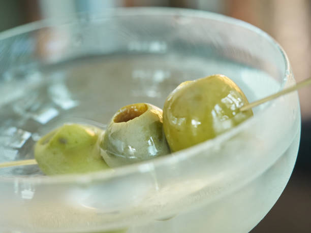 Green olives on a stick in a martini glass shallow depth of field stock photo