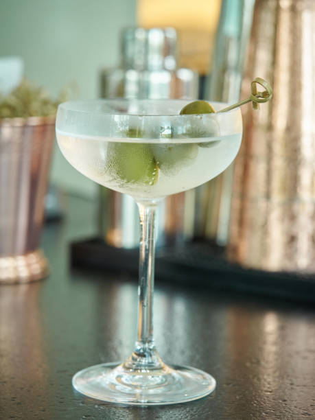 Dirty martini mixed drink in a martini glass with three green olives on a string stock photo