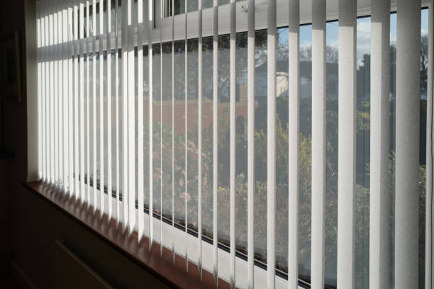 istock White vertical blinds slats hanging in front of double glazed white frame window. The slats have no cords at the bottom. The focus is shallow. 1191498518