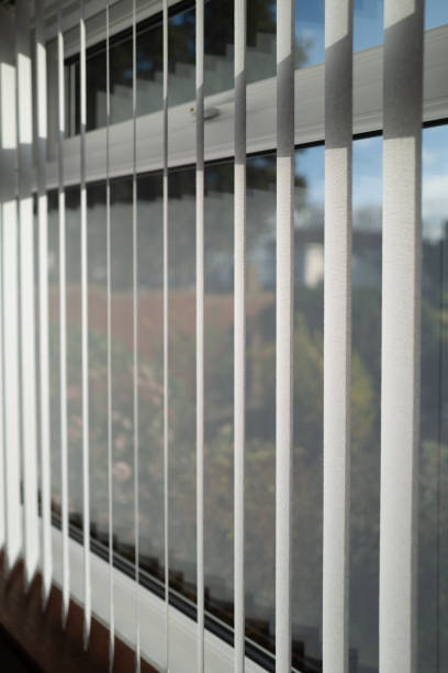 istock White vertical blinds slats hanging in front of double glazed white frame window. The slats have no cords at the bottom. The focus is shallow. 1191498526