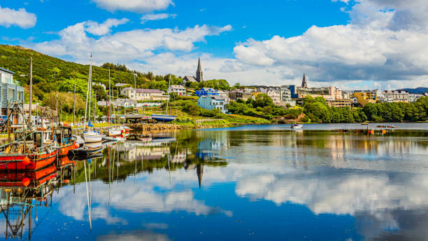 пирс в порту клифден во время прилива, лодки на якоре с зеркальным отражением в воде - республика ирландия стоковые фото и изображения